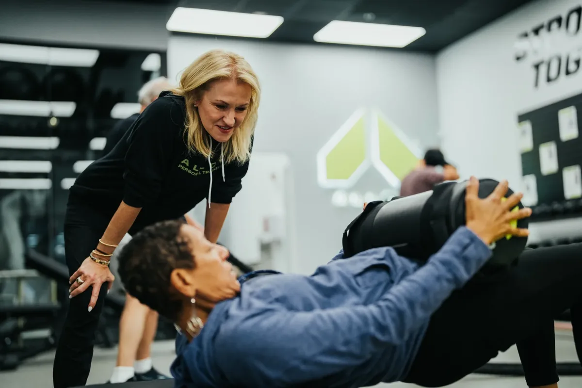 Trainer coaches a member through a sandbag exercise at Alloy Personal Training — Billings, MT