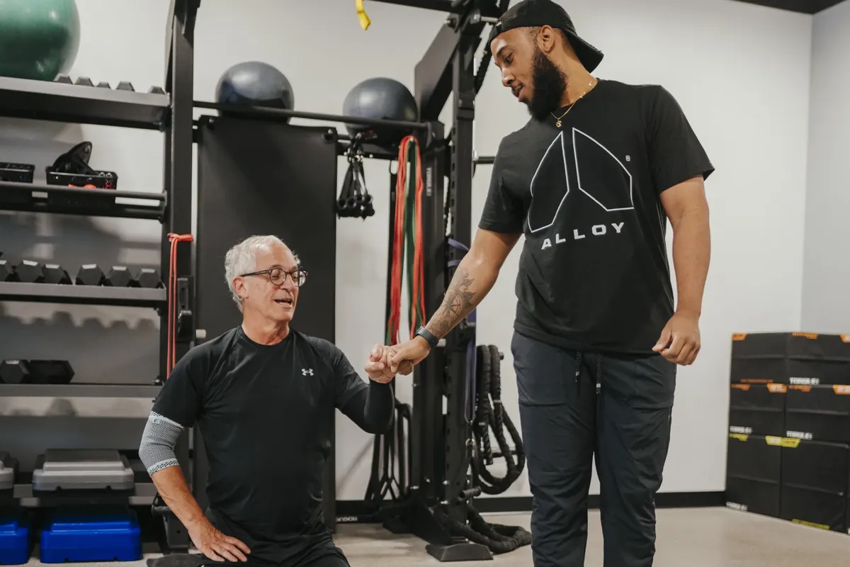 A coach fist-bumps an older member during a training session
