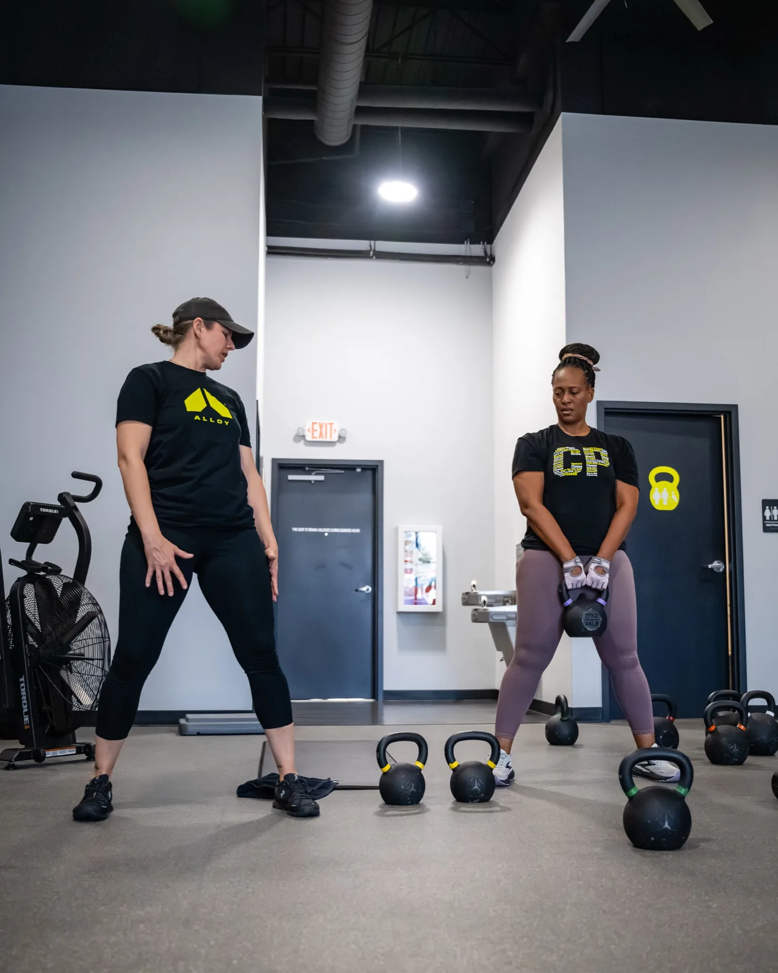 A coach walks a member through a kettlebell deadlift setup at Alloy Personal Training Billings
