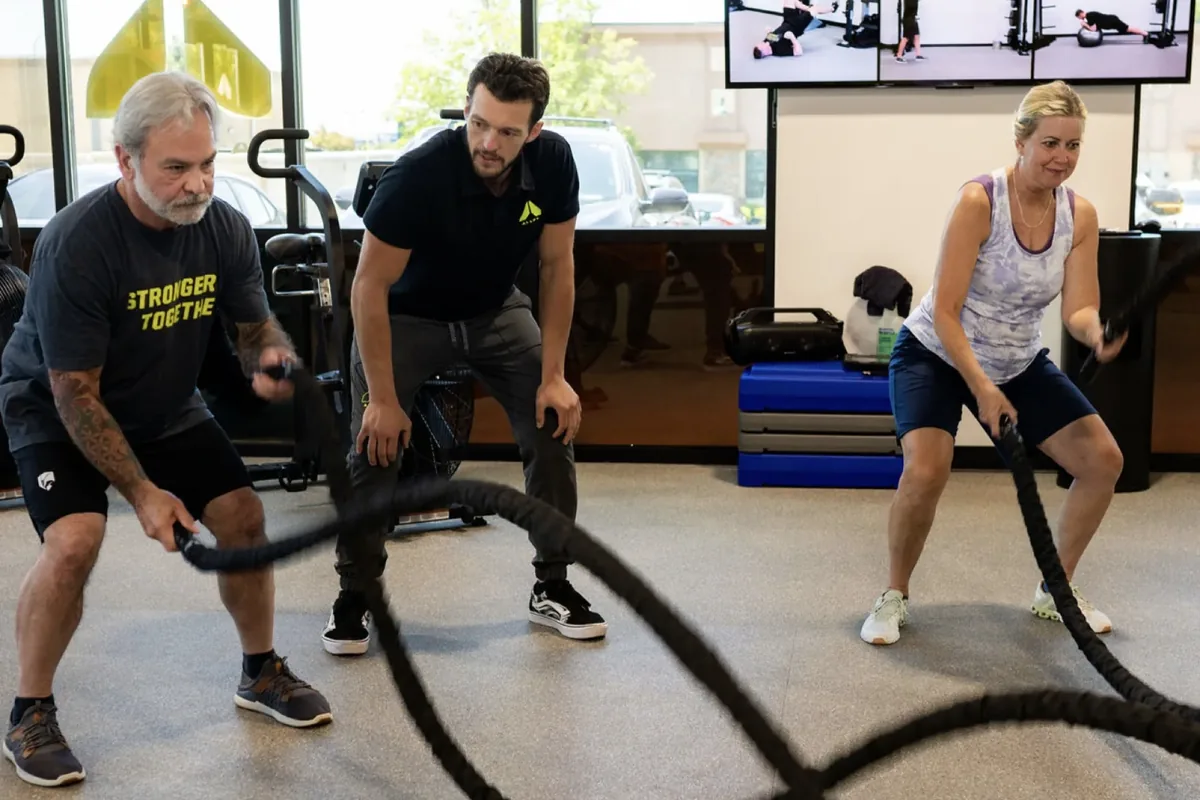 Members work battle ropes with a coach at an Alloy Personal Training session — Billings, MT