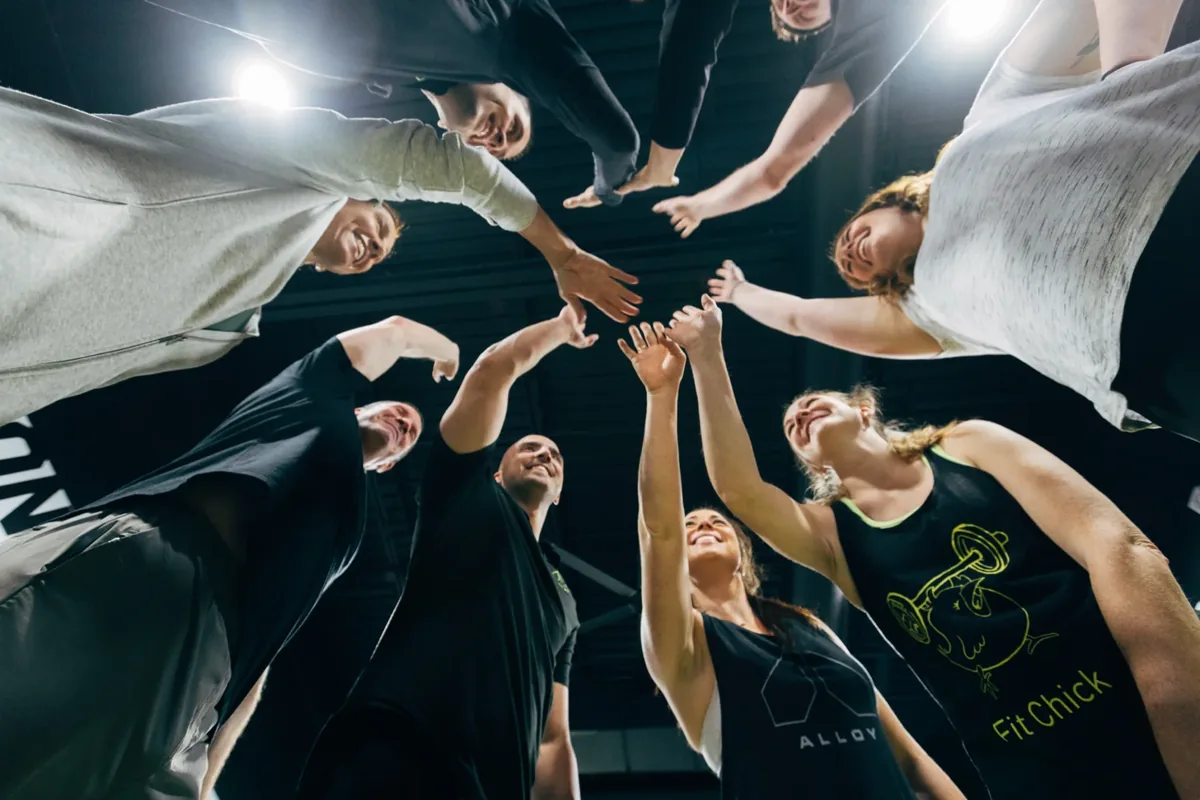Alloy Personal Training members stack hands in a group huddle — Billings, MT